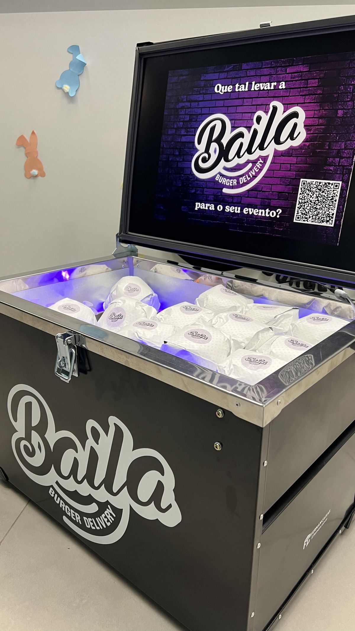Box térmica personalizada Baila aberta, iluminada em roxo, cheia de burgers embrulhados prontos para servir